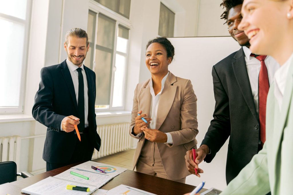 A diverse group of professionals collaborating in a bright office setting, engaging in teamwork and discussion.
